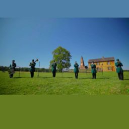 Six college-age men in bright green uniforms of antebellum American style are playing