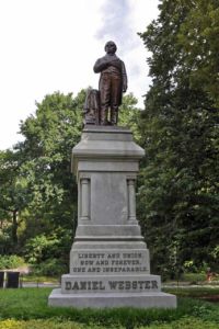 statue of man in double-breasted suit with one had placed partially into his jacked between two of its buttons and on the statue's base the words Liberty and Union, Now and Forever, One and Inseparable. Daniel Webster.