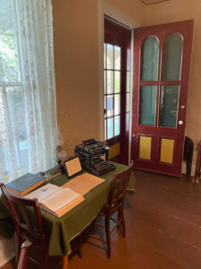 a wooden table with a green table cloth and an antique typewriter and two books on top